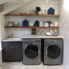 a washer and dryer in a small room with open shelving on the wall