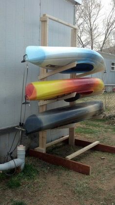 three surfboards are stacked on top of each other in front of a building with a water hose attached to it