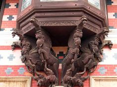 an intricately carved clock on the side of a building with elephants and people around it