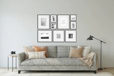 a living room with a couch, lamp and pictures on the wall above it in black and white