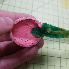 a person is holding a piece of pink and green paint with a green brush sticking out of it