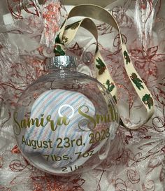 a glass ornament with a wedding date on it sitting on a white fabric