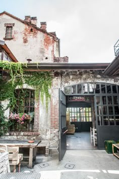 the entrance to an old building with plants growing on it's walls and doors