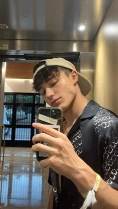 a young man is looking at his cell phone in the elevator while wearing a hat