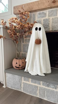 a fake ghost sitting on top of a mantle next to a potted plant and pumpkin