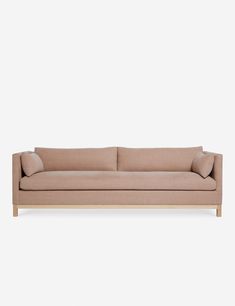 a beige couch with two pillows on the back and one arm folded up in front