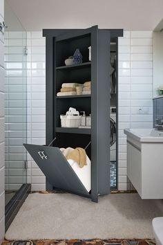 an open cabinet in the middle of a bathroom with towels and other items on shelves