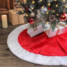 a small christmas tree with presents under it on a red and white round rug in front of a fireplace