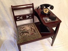 an old telephone sits on a small wooden table next to a chair with a rug