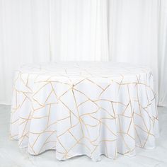 a white table cloth with gold lines on it, sitting in front of a curtain