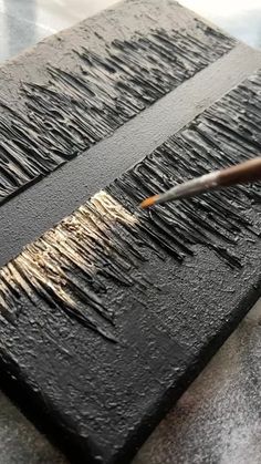 a person is using a brush to paint on a piece of black paper with white writing