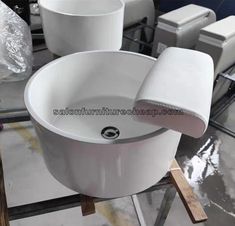 a white sink sitting on top of a table next to other sinks and containers in the background