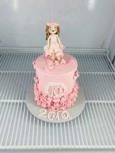 a pink birthday cake with a doll sitting on top of it in the fridge for someone's 90th birthday