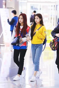 two young women are walking through an airport