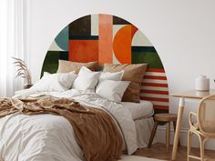 a bed with white sheets and pillows in front of a colorful headboard on the wall