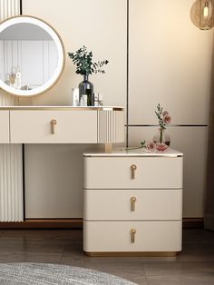 a white dresser sitting next to a mirror on top of a wooden floor