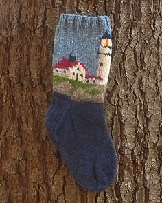 a sock hanging on a tree with houses in the background and blue socks attached to it