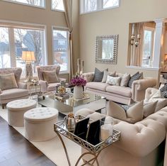 a living room filled with lots of furniture and large windows in the wall behind it