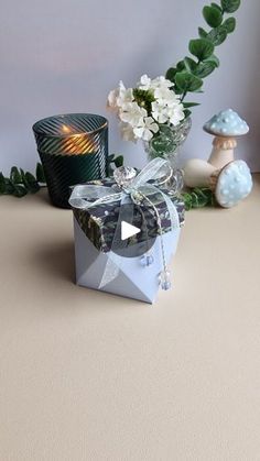 a gift box with a candle and flowers in it on a table next to other decorations