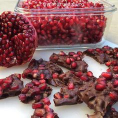 chocolate and pomegranates are on the table next to a glass container