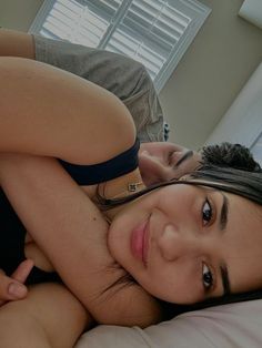 a woman laying on top of a bed with her arm around another person's head