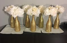 five gold vases with white flowers in them