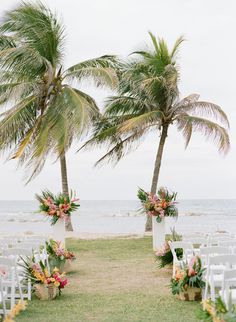 the wedding ceremony is set up with white chairs and palm trees in front of the ocean