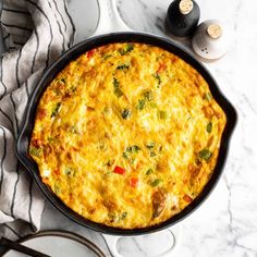 an omelet in a cast iron skillet on a marble countertop next to utensils