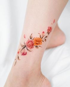 a woman's foot with flowers and leaves on the bottom part of her leg