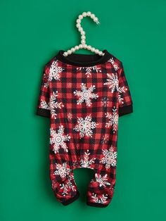 a red and black plaid snowflake onesuit hanging on a green wall