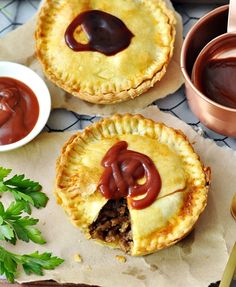 two pies with chocolate sauce on top and some other dessert items in bowls next to them