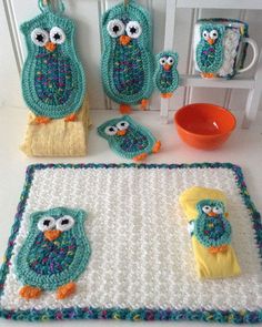 crocheted owls sitting on top of a table next to cups and saucers