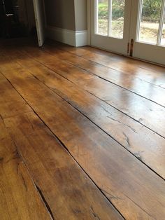 an empty room with wood flooring and two large doors leading to the front door