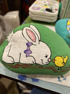 painted rocks with an image of a bunny and chick on them are sitting on a table