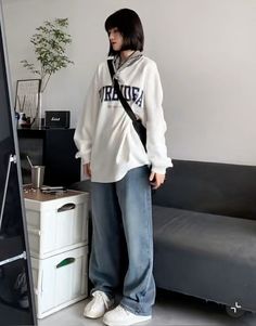 a woman standing in front of a tv wearing a white shirt and jeans with the words trouble on it