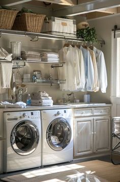 a washer and dryer in a room with clothes hanging on the rack above it