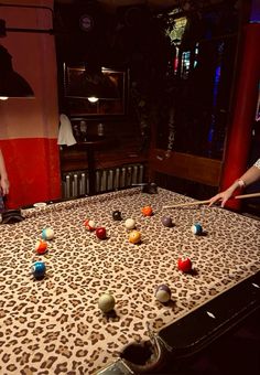 two people are playing with balls on an old style table in a room that is decorated with leopard print