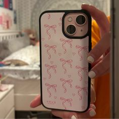 a woman holding up her phone case with pink bows on the front and back cover