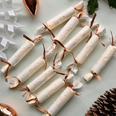 some white candles with gold dots on them are next to pine cones and christmas decorations