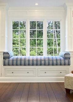 a window seat in the corner of a room with wooden floors and white walls, along with two windows