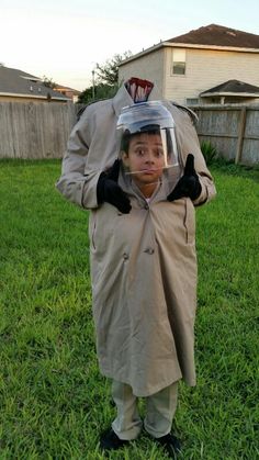 a man in a raincoat with a plastic helmet on his head, standing in the grass