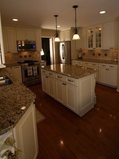 a large kitchen with white cabinets and granite counter tops