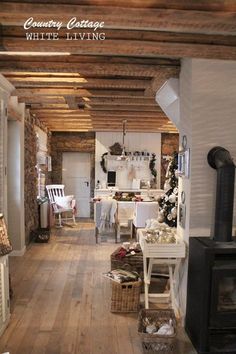 an old fashioned kitchen and living room with wood flooring, exposed beams and white walls