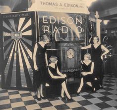 three women in black dresses are standing next to a machine with the words edison radio on it