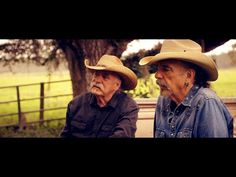 two men sitting on a bench wearing cowboy hats