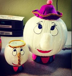 two white pumpkins with faces painted on them