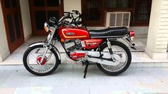 a red and black motorcycle parked in front of a building