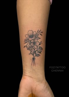 a woman's arm with a flower tattoo on the left side of her wrist