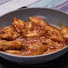 some food is cooking in a frying pan on the stove top with red sauce