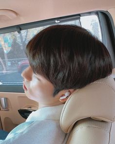 a person with ear buds in the back seat of a car looking out the window